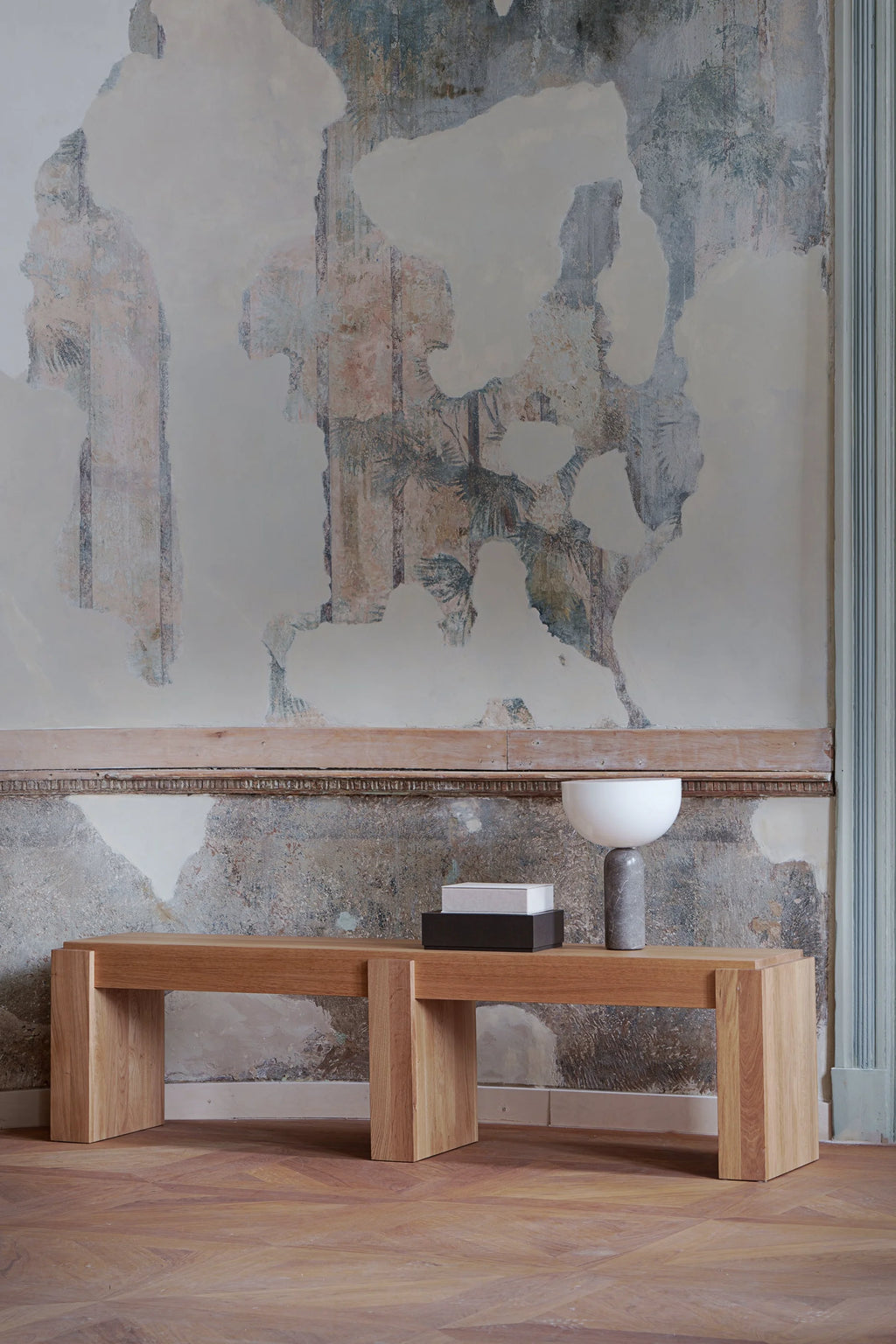 TAMO Pura 160 Bench in a lifestyle shot, showcasing its natural light brown solid oak wood with a visible grain, featuring a clean, rectangular design with thick, sturdy legs. A modern, premium furniture piece.