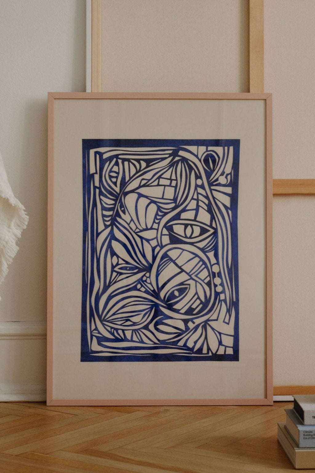 The Poster Club Wonderland Blue, a deep blue abstract line art print featuring organic, flowing shapes and intricate patterns, set against a cream-colored background. This modern abstract poster is framed in a light natural wood frame with a crisp white mat. Perfect for adding a contemporary artistic touch to gallery walls in living rooms, bedrooms, or home offices.