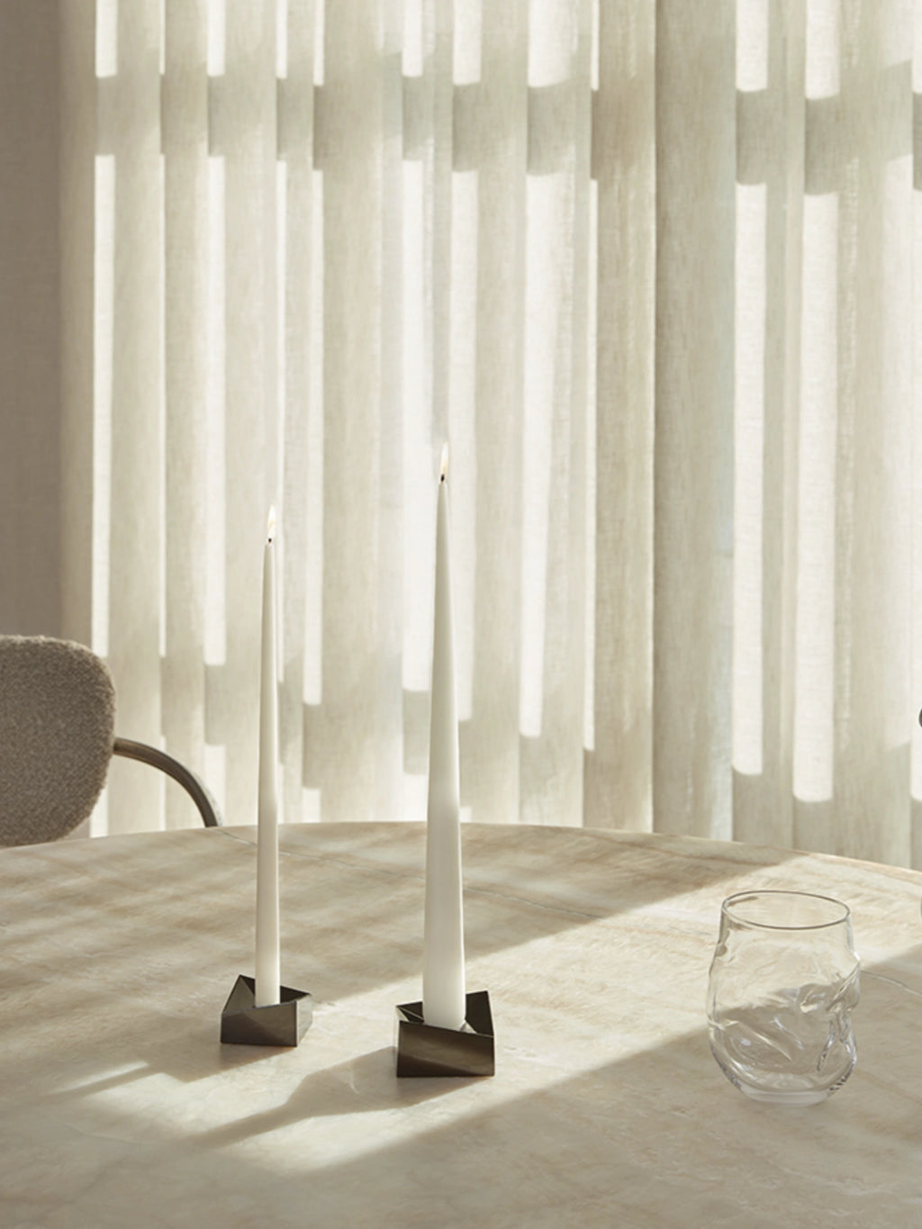 Stoff Nagel Reflect Candle Holder, a modern minimalist taper candle holder crafted from dark polished metal with a distinctive geometric, faceted design, creating a sculptural effect. Ideal for contemporary dining table centerpieces, elegant mantel decor, or minimalist shelf styling in design-led homes.