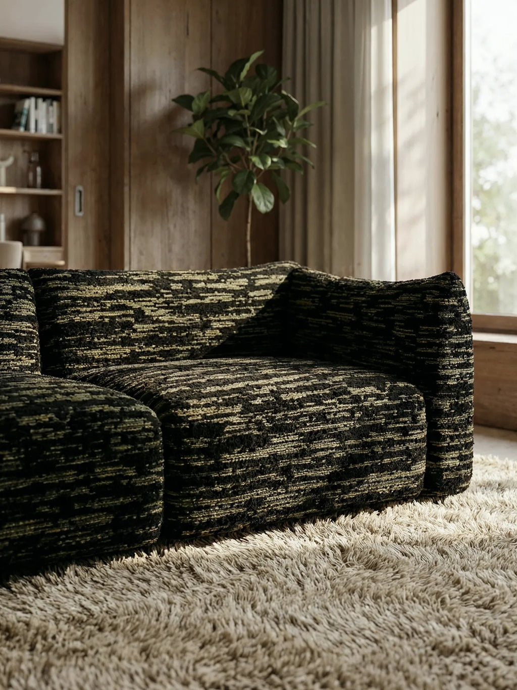 TCL Studios Rèverie Sofa, a contemporary modular sofa featuring a rich black and olive green textured upholstery fabric with a chunky, abstract stripe pattern, designed with a low-profile silhouette and deep, inviting seating. This organic modern sectional sofa is perfect for creating a cozy yet sophisticated focal point in a minimalist living room or spacious lounge area.