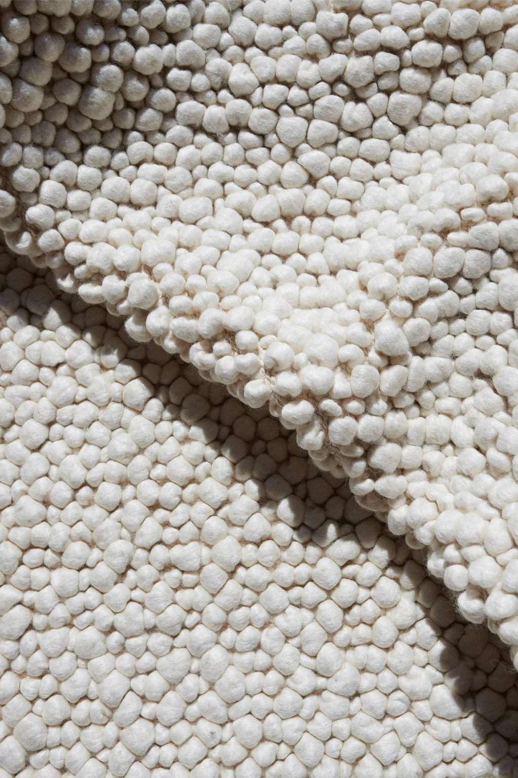 Linie Design Sigga Rug, a cream-colored, highly textured wool area rug featuring a unique pebble-like surface crafted from chunky, felted wool nubs in natural undyed off-white tones. This plush and organic modern rug offers a soft, inviting feel underfoot, perfect for adding warmth and Scandinavian style to cozy living rooms, minimalist bedrooms, or japandi-inspired spaces.