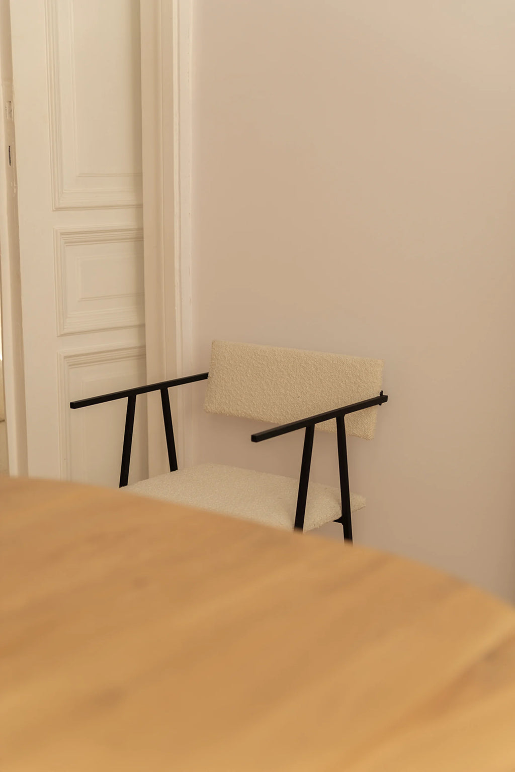 NG DESIGN Object 058 Chair, a modern, off-white boucle upholstered chair with sleek black metal frame and arms, positioned in a contemporary living space. Premium seating for sophisticated interiors.