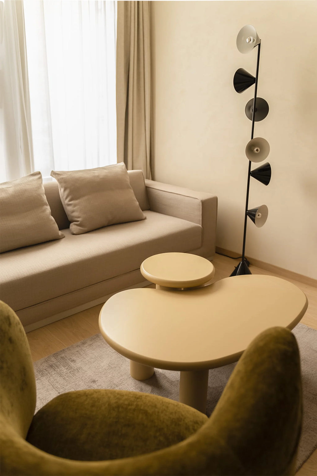 NG DESIGN Object 061 Coffee Table in a lifestyle setting, showcasing its unique kidney-bean shape and integrated circular riser in a matte beige finish. This premium modern coffee table is ideal for contemporary living spaces.