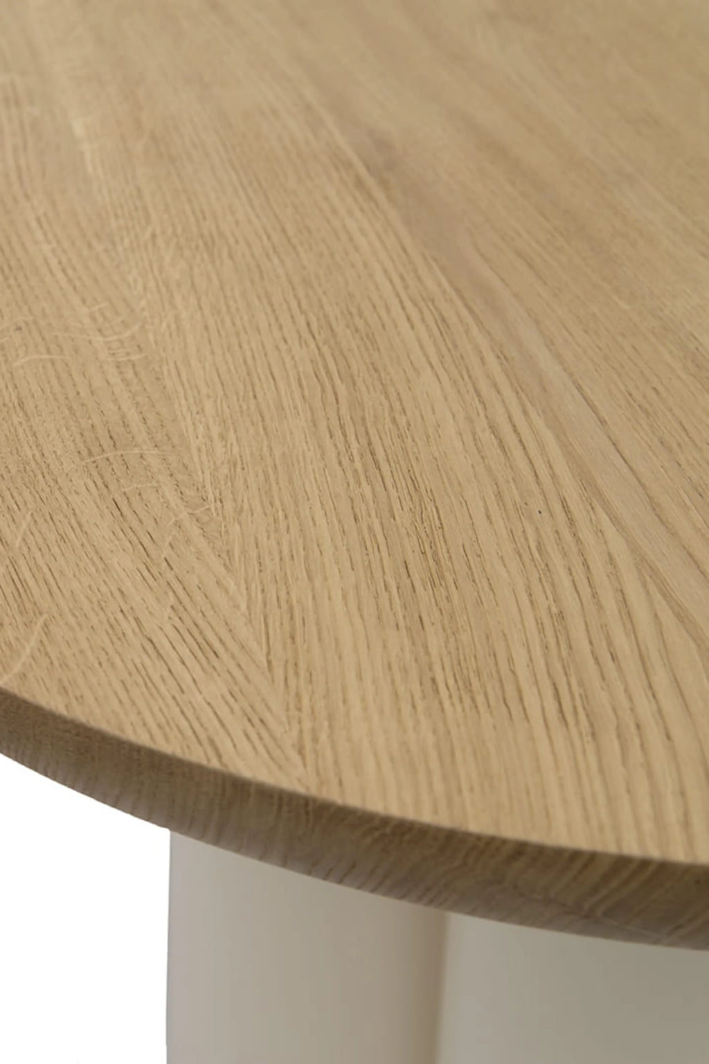 NG DESIGN Object 071 Dining Table: Close-up of modern round light brown oak tabletop with pronounced wood grain, resting on a subtle light-colored base, showcasing premium solid wood craftsmanship. Ideal for contemporary dining spaces.