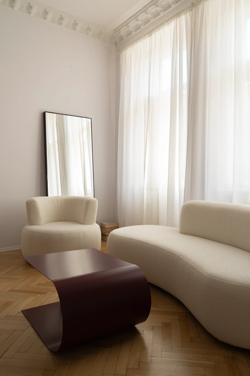 NG DESIGN Object 051 Lounge Chair shown in an elegant room setting. It features a curved, off-white textured boucle fabric, accompanied by a matching chair and a burgundy metal coffee table. Perfect for modern luxury interiors.