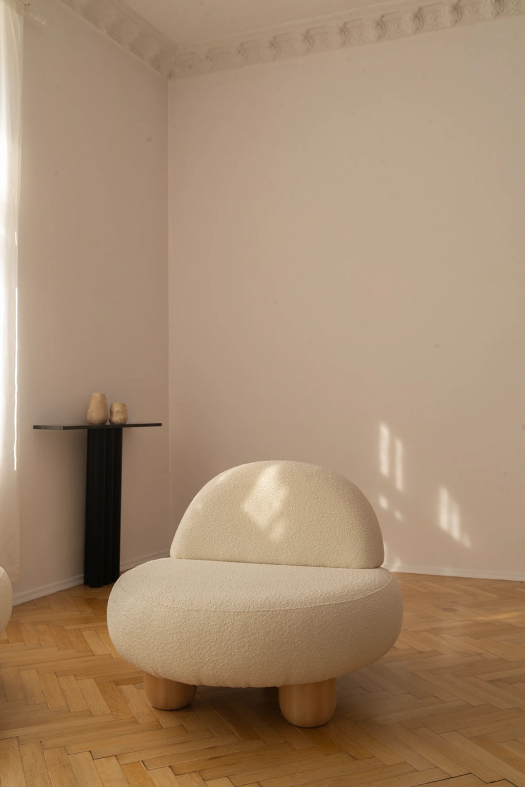 White chair in a minimalistic room with a wooden floor and white walls.