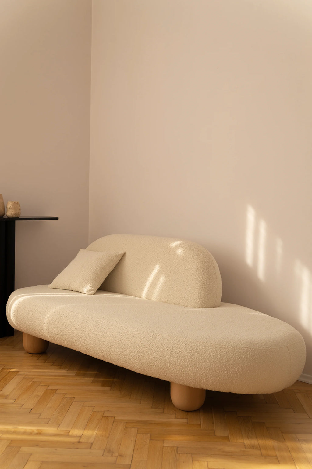 NG DESIGN Object 047 Sofa in champagne bouclé fabric, featuring a curved back and round wooden legs, with a matching throw pillow on a herringbone floor. Perfect for modern living spaces.