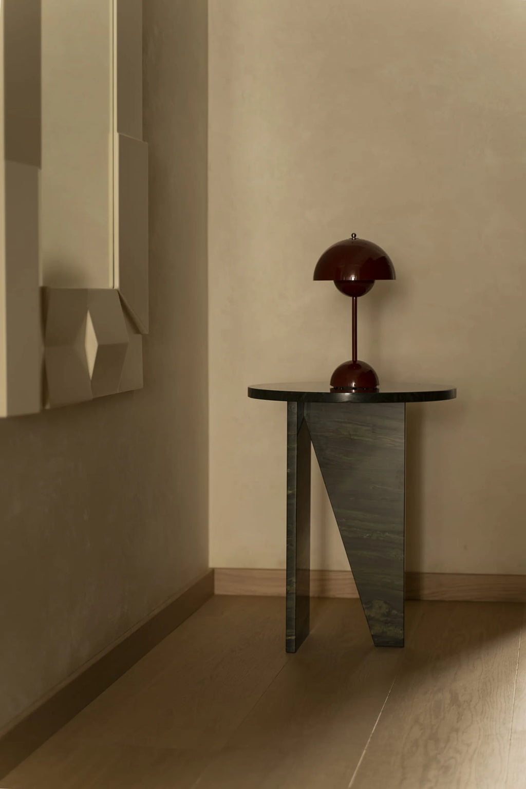 NG DESIGN Object 066 Side Table, a luxury black marble accent piece with an angular, geometric base and round top, styled with a sophisticated reddish-brown lamp. Ideal for modern living spaces.
