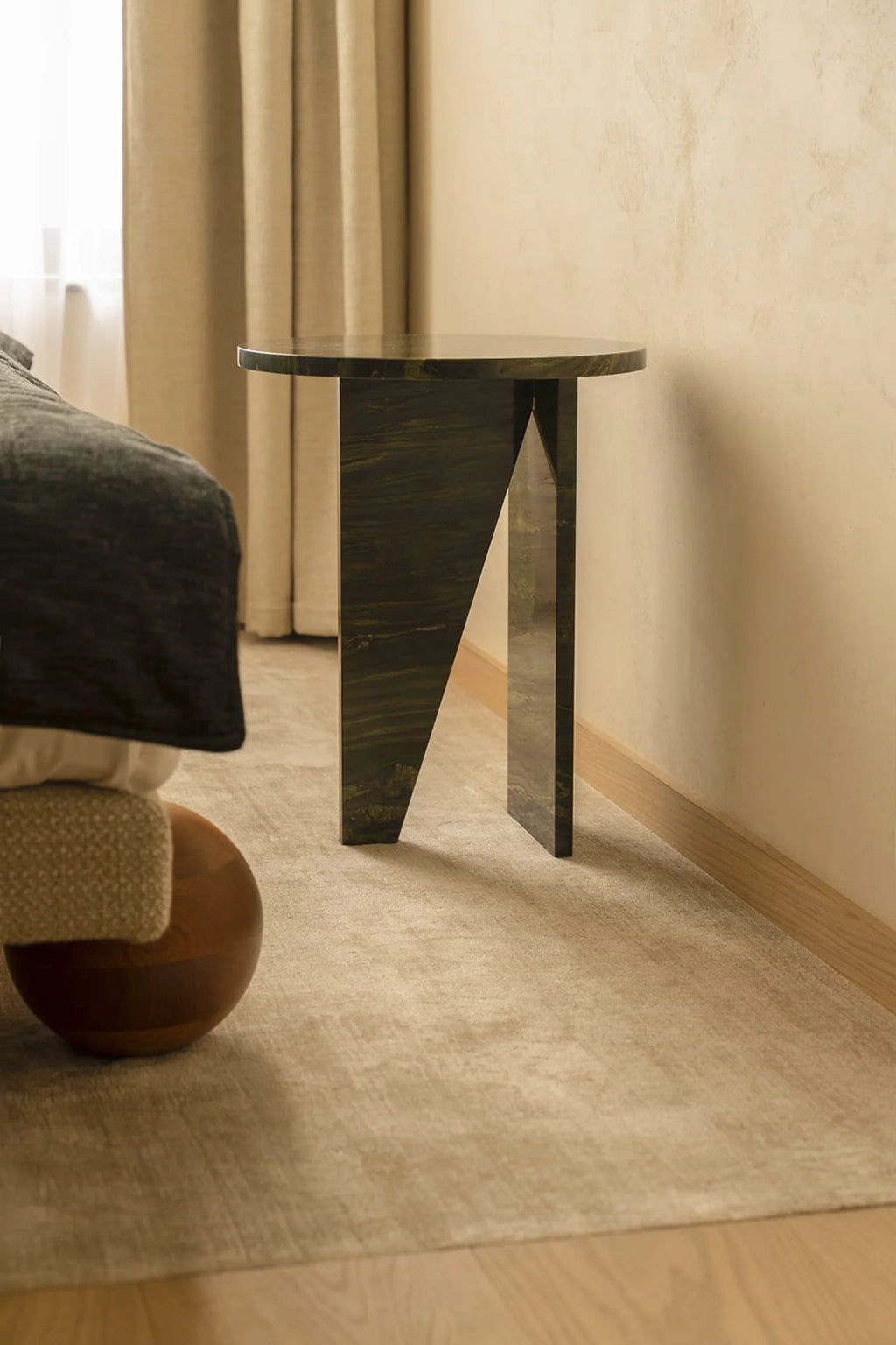 NG DESIGN Object 066 Side Table, a luxury dark green marbled stone table with a round top and geometric base, displayed beside a bed on a neutral rug. Ideal for a sophisticated bedroom or living space.