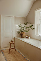 Bathroom with a bathtub, plant, and stool.