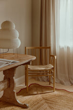 Wooden table with a chair in a room with curtains and a lamp.
