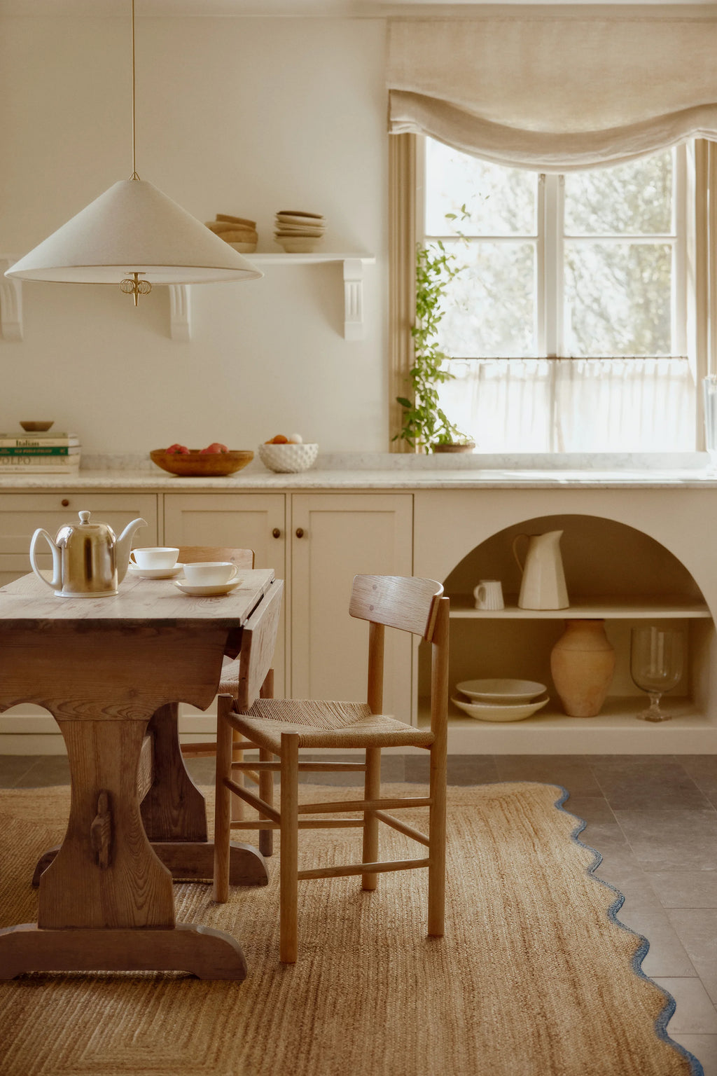 Nestled kitchen with wooden table and chairs, white walls, and a window.