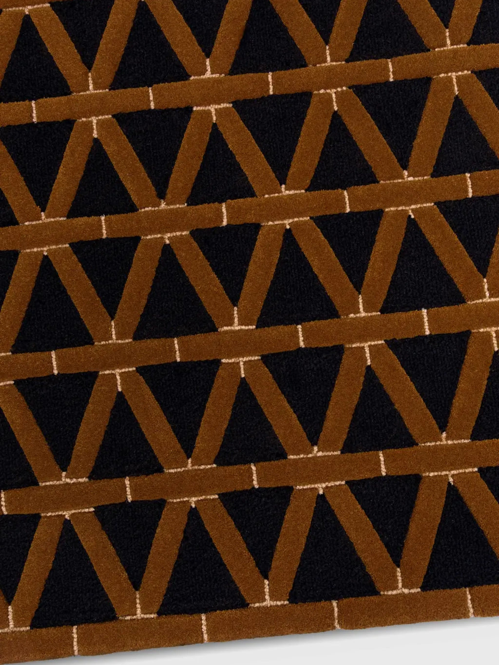 alp_ Secadero Rug, a luxurious contemporary area rug featuring a striking geometric pattern of interlocking V-shapes in plush, raised cognac brown pile against a deep black background, accented with fine cream lines. This bold, textured wool-blend rug creates a sophisticated focal point for modern living rooms, Art Deco-inspired dining rooms, or stylish bedrooms.