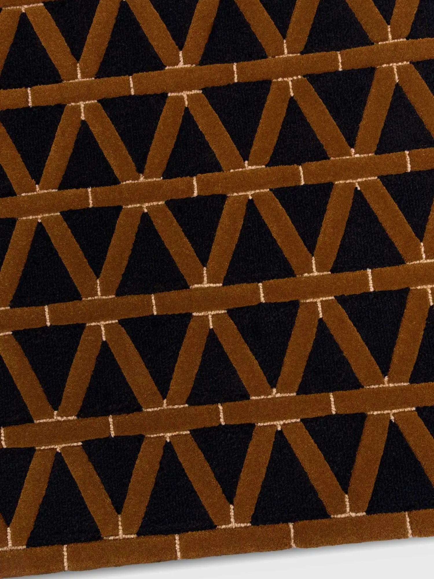 alp_ Secadero Rug, a luxurious contemporary area rug featuring a striking geometric pattern of interlocking V-shapes in plush, raised cognac brown pile against a deep black background, accented with fine cream lines. This bold, textured wool-blend rug creates a sophisticated focal point for modern living rooms, Art Deco-inspired dining rooms, or stylish bedrooms.