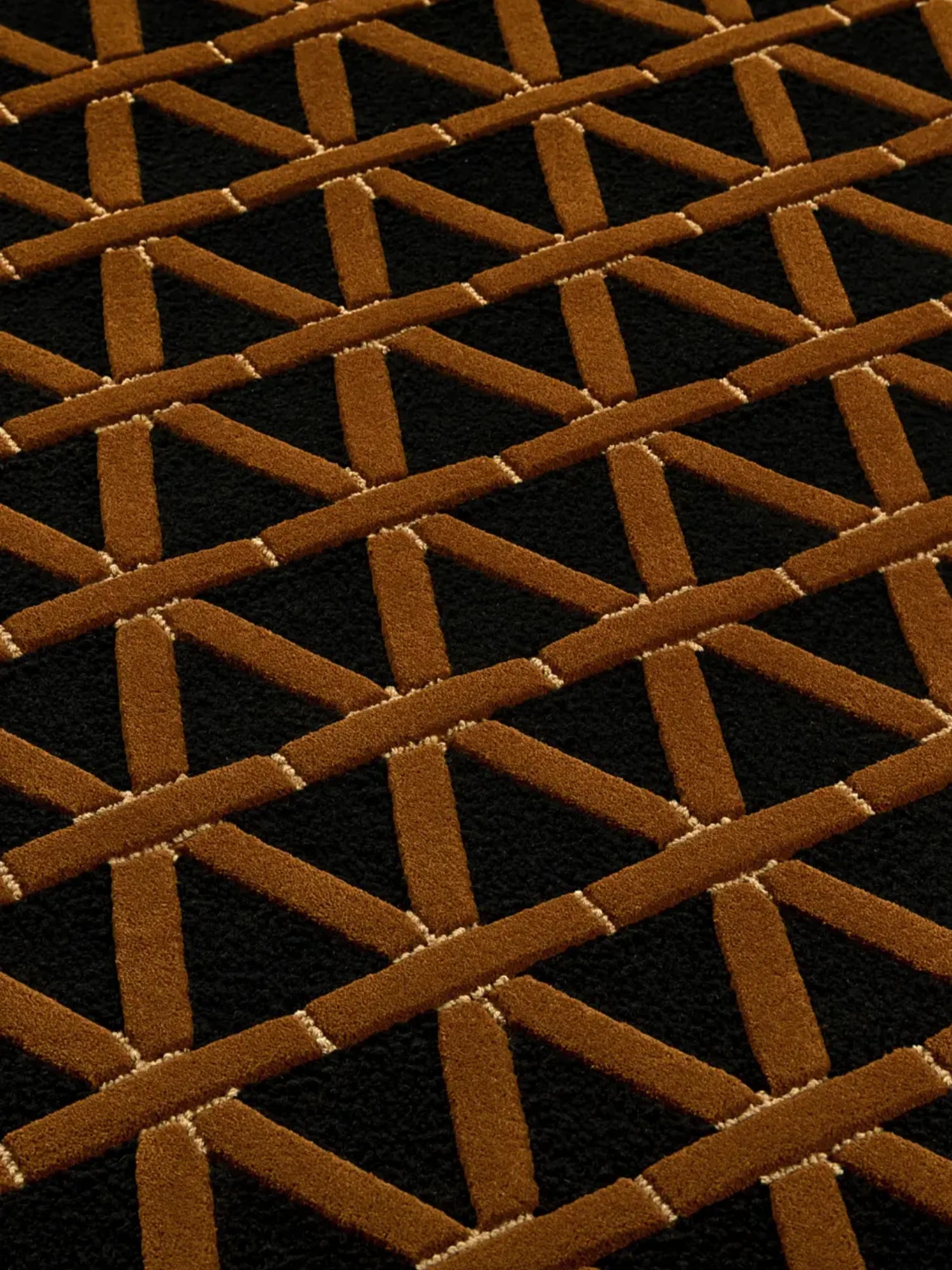 alp_ Secadero Rug, a striking black and brown geometric rug featuring a bold interlocking Art Deco-inspired pattern with textured tufted pile in rich cognac brown against a deep black background, accented by subtle cream-colored lines. This contemporary area rug is perfect for adding a sophisticated graphic statement to modern living rooms or elegant dining spaces.