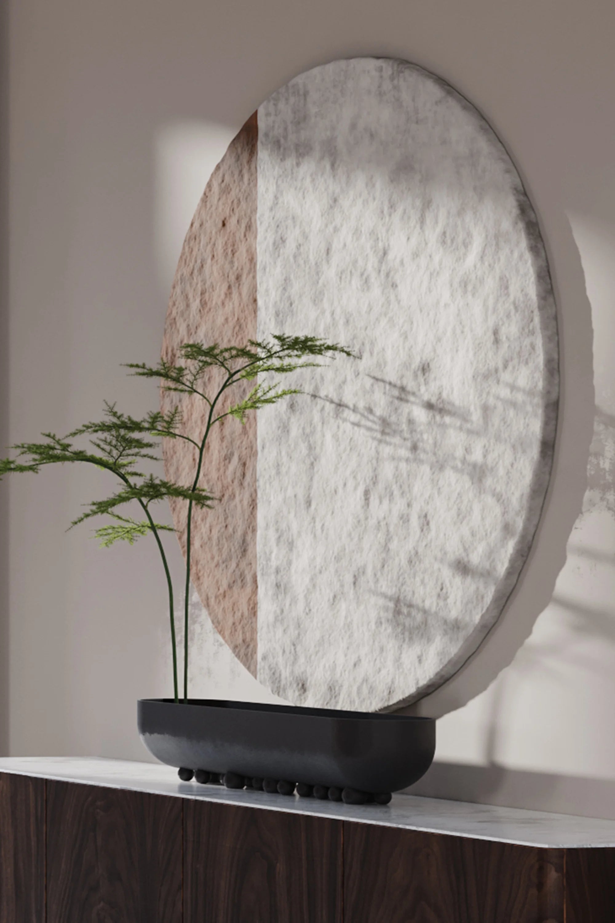 Decorative round mirror with a textured surface on a shelf with a plant.