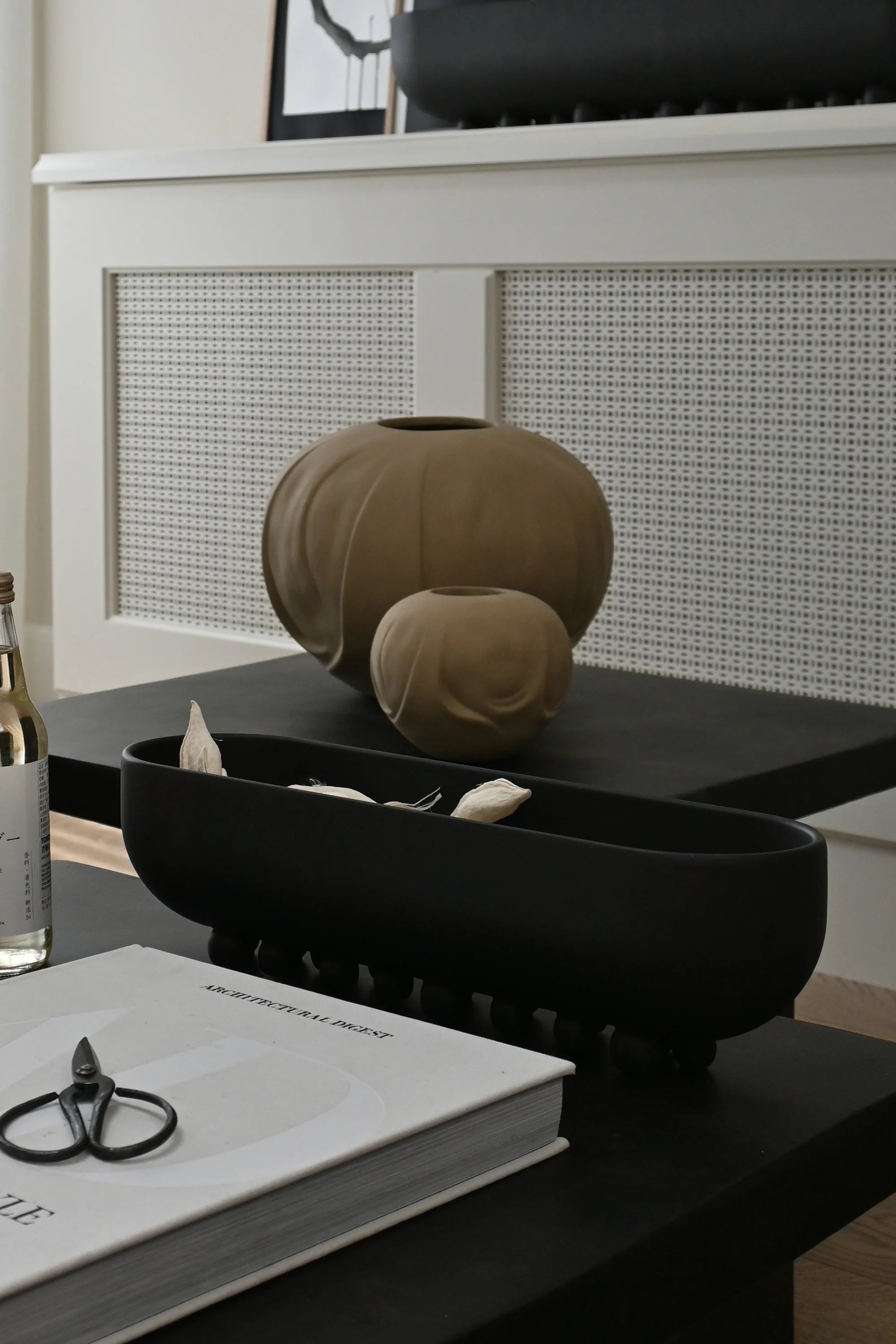Decorative vases on a table with a book and scissors in the foreground