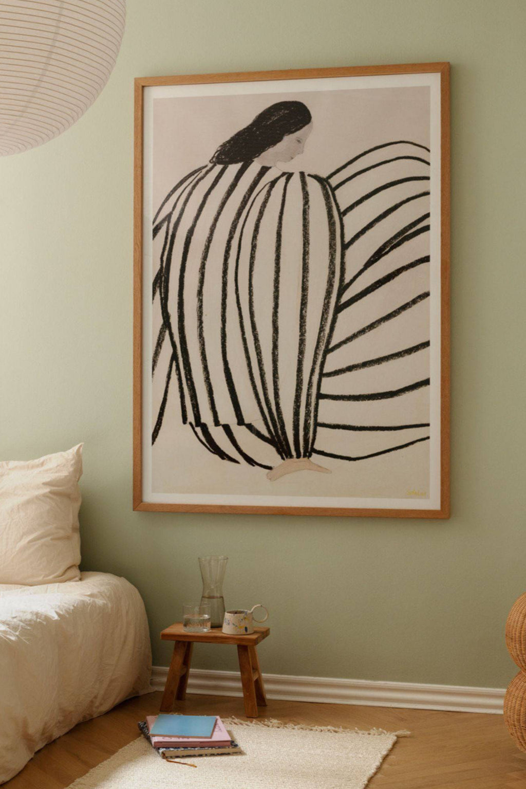 The Poster Club You, a modern minimalist abstract figurative art print featuring bold black charcoal-like stripes forming a seated figure against a soft beige background. It is elegantly framed in a light natural oak frame, enhancing its contemporary Scandinavian aesthetic. Perfect as striking wall art for a minimalist bedroom, Nordic living room, or a curated gallery wall.