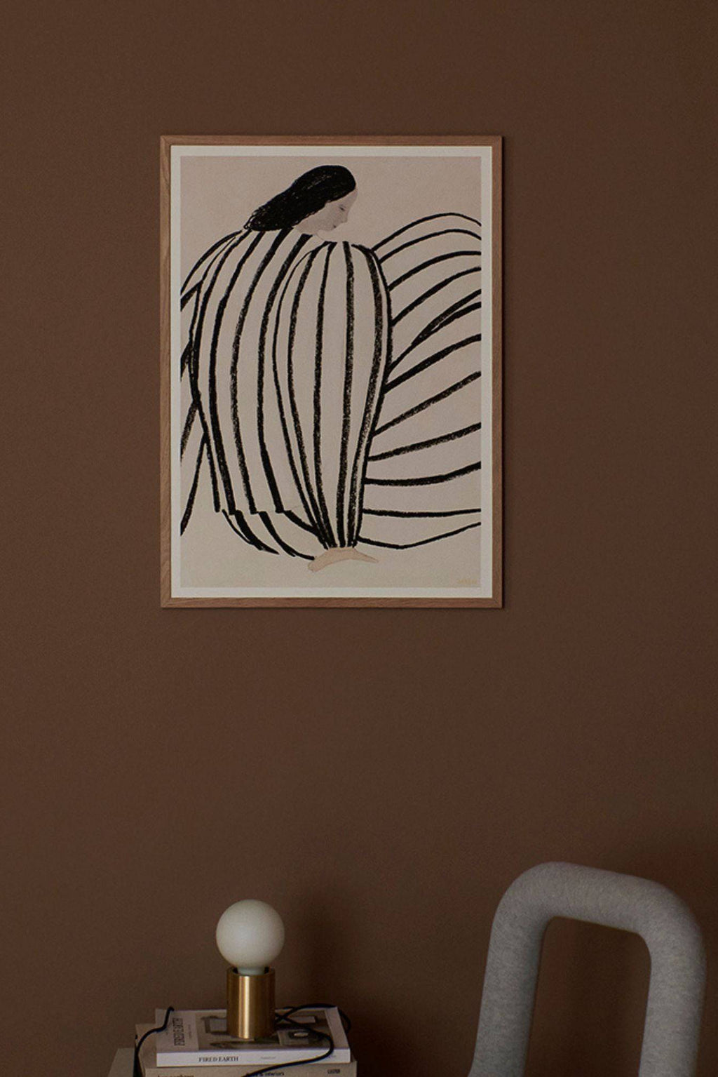 The Poster Club You, an abstract figurative art print featuring a seated figure with dark hair and bold, hand-drawn black stripes forming their body, set against a warm beige background. This modern minimalist poster, framed in light natural oak, offers a sophisticated Scandinavian aesthetic with organic lines. Perfect for contemporary gallery walls, bedrooms, or living rooms seeking understated wall art.