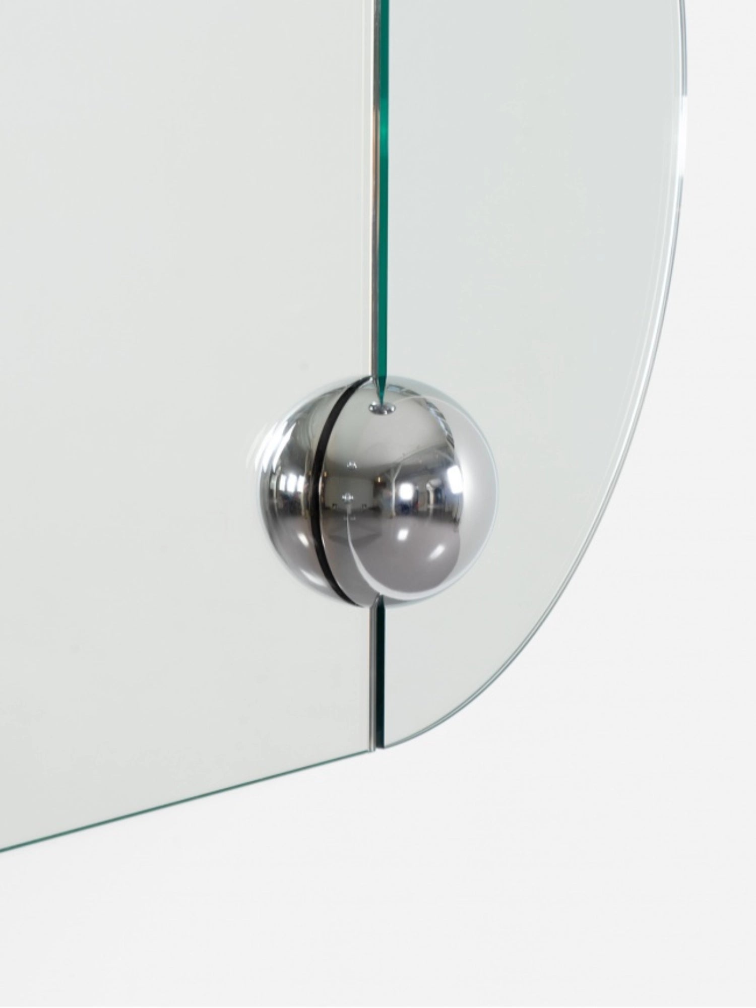 Moustache Sphera Oblong Mirror, a detailed close-up of a polished chrome spherical fastener securing two glass panels of the elegant frameless mirror, highlighting its modern design.