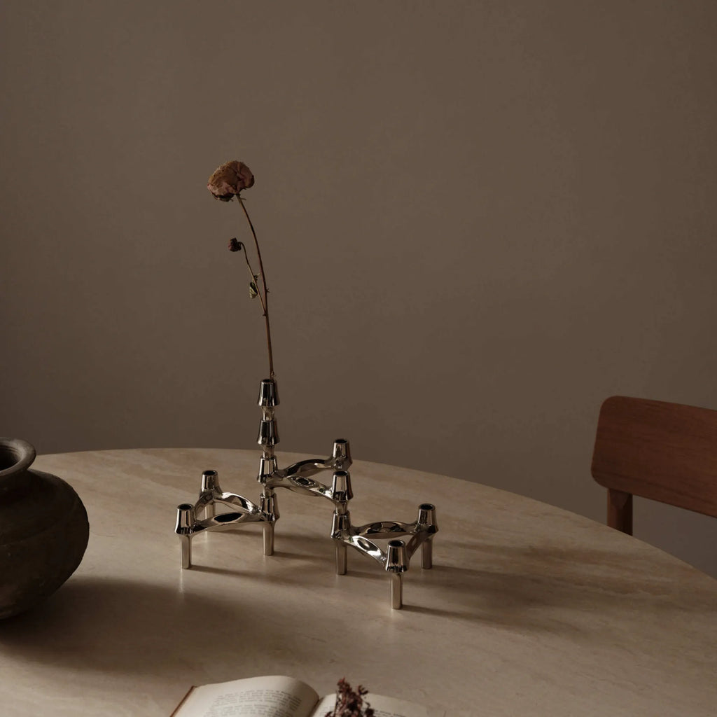 Stoff Nagel BMF Vase, an iconic mid-century modern modular candle holder crafted from polished chrome metal, featuring a sculptural, interlocking design with three prongs and candle sockets per unit. This stackable silver metal piece functions as a decorative vase or a dynamic centerpiece, reflecting light with its smooth, reflective surface. Perfect for brutalist, industrial chic, or contemporary living room and dining table styling.
