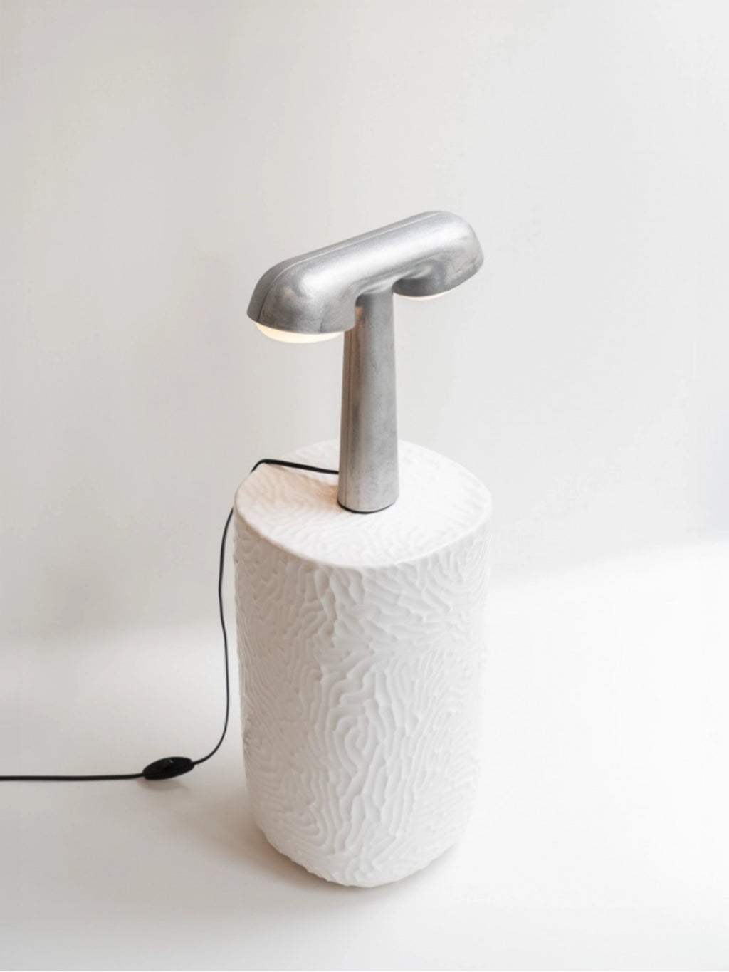 Moustache TGV Lamp, a distinctive modern table lamp featuring a textured white ceramic base with an organic, wave-like pattern and a sleek, T-shaped brushed silver metal lamp head. This sculptural white and silver lamp provides contemporary accent lighting, perfect as a modern desk lamp or bedside table lamp for living rooms, bedrooms, or home offices.