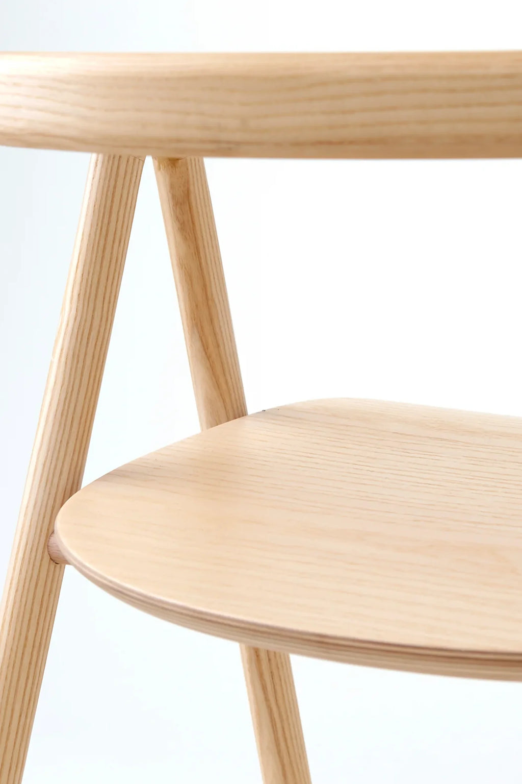 Made by Choice Laakso Dining Chair, a detailed close-up of the light natural wood seat and curved backrest, showcasing the smooth finish and elegant craftsmanship of this minimalist design, on a white background.