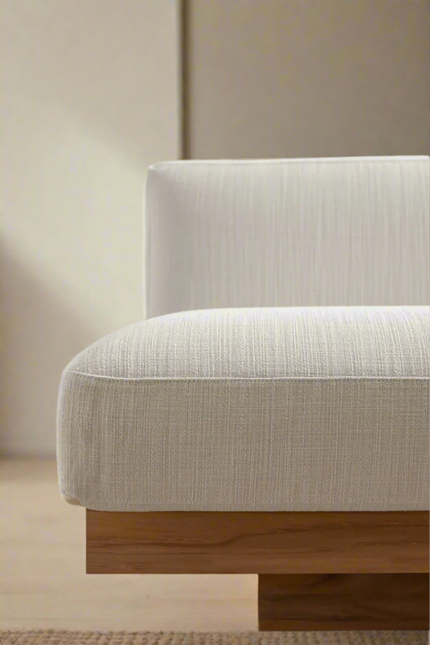 Beige upholstered chair with wooden base against a white wall