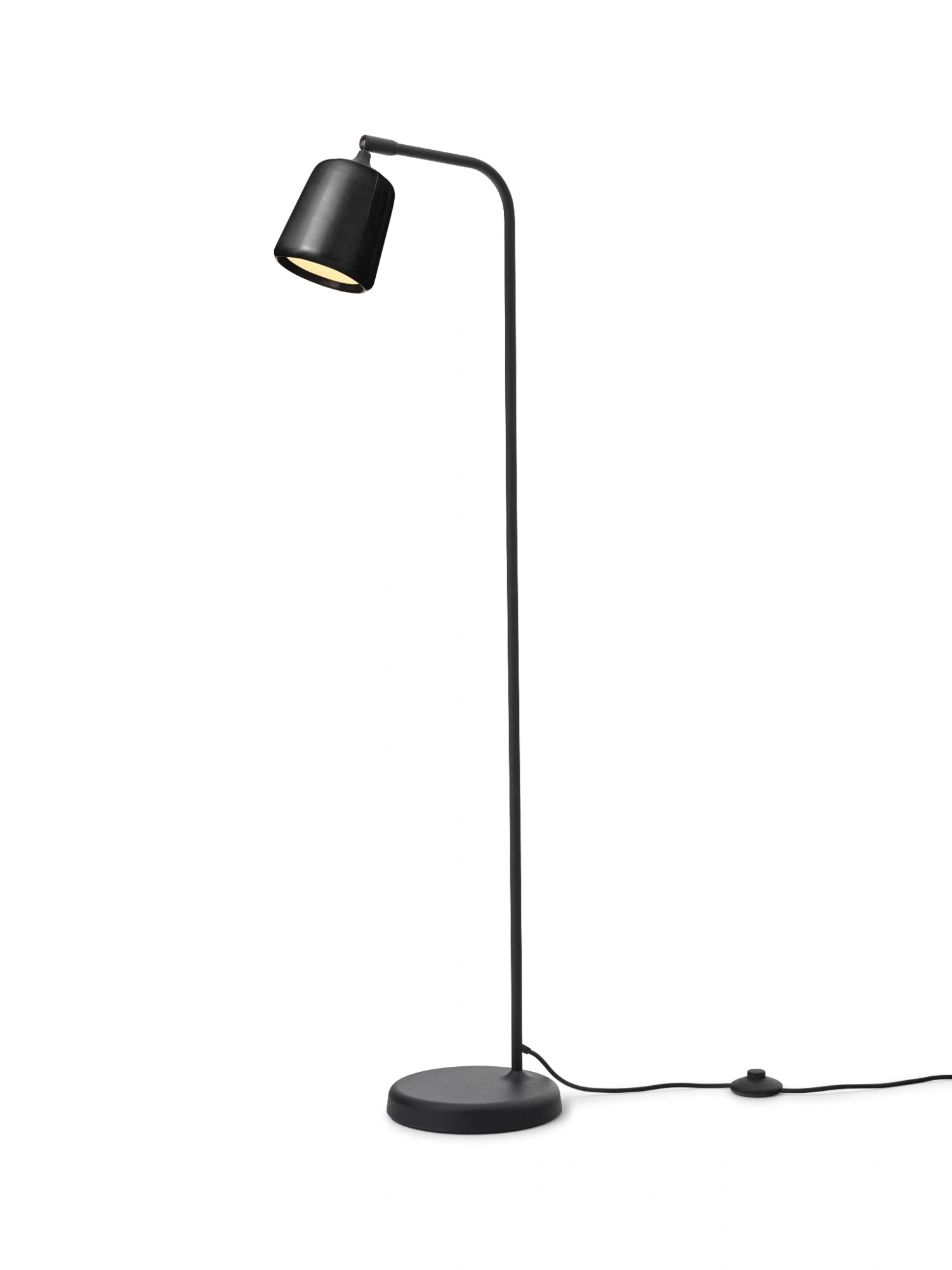 New Works Material Floor Lamp, a contemporary minimalist floor lamp featuring a clean architectural design with a matte black metal finish throughout its conical shade, slender curved arm, and stable round base, casting a focused, warm.