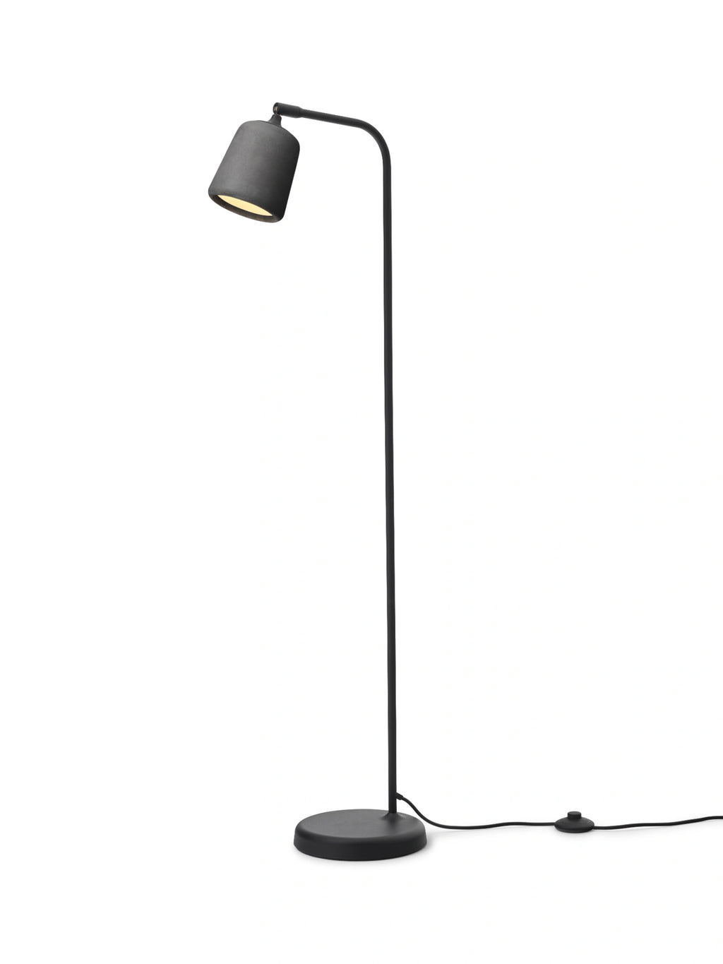 New Works Material Floor Lamp, a modern minimalist floor lamp featuring a distinctive dark grey textured shade, likely concrete or stoneware, paired with a slender matte black metal frame and a round stable base. This Scandinavian-inspired industrial chic floor lamp is perfect for contemporary living rooms, cozy reading nooks, or stylish home office lighting.