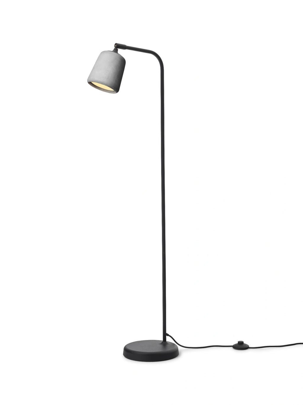 New Works Material Floor Lamp, a modern minimalist floor lamp featuring a light grey concrete shade with a textured finish and a slender matte black metal stem, base, and curved arm. This industrial-style floor lamp provides focused light, perfect for a reading nook in a Scandinavian living room or contemporary bedroom.