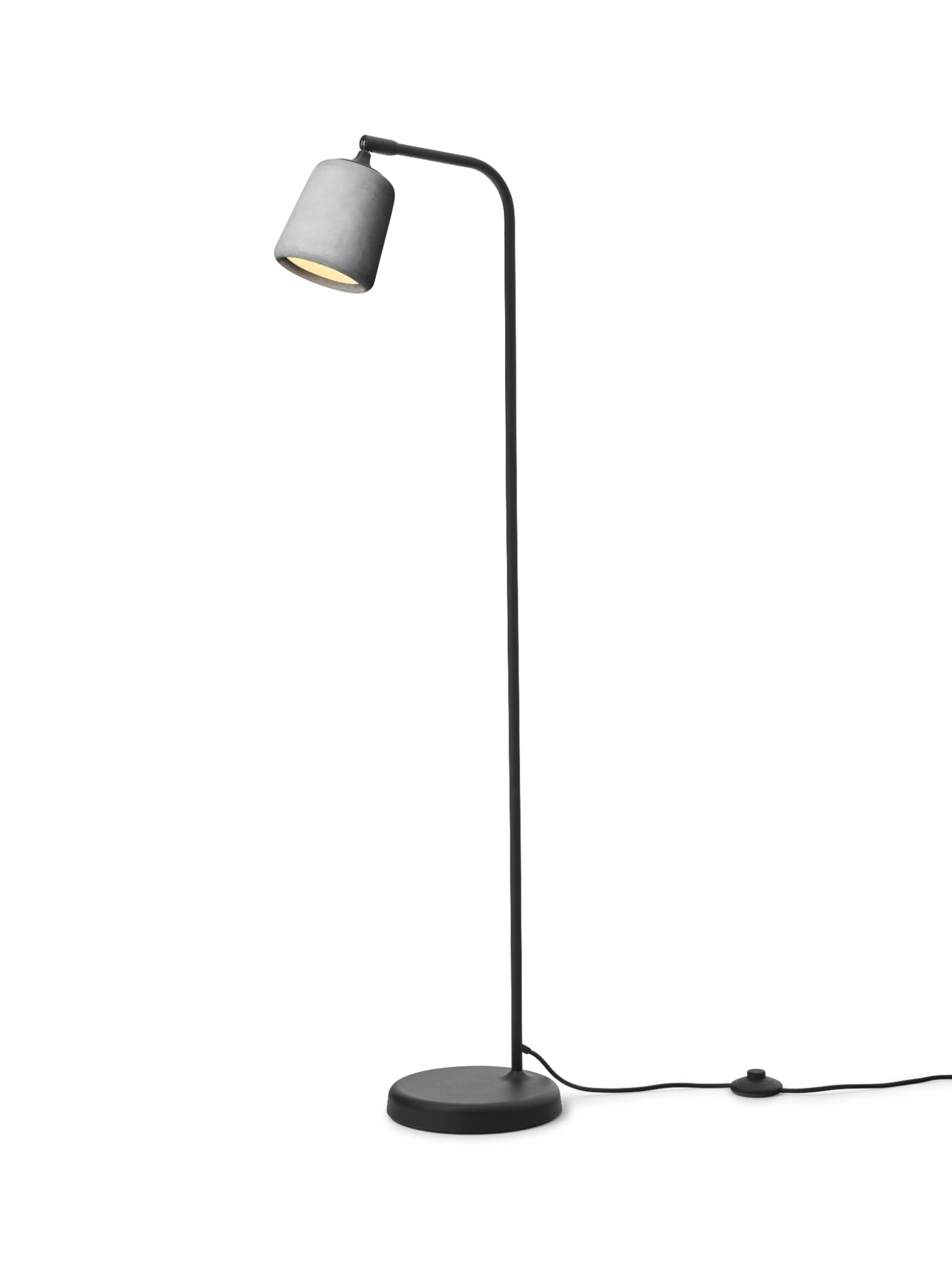 New Works Material Floor Lamp, a modern minimalist floor lamp featuring a light grey concrete shade with a textured finish and a slender matte black metal stem, base, and curved arm. This industrial-style floor lamp provides focused light, perfect for a reading nook in a Scandinavian living room or contemporary bedroom.