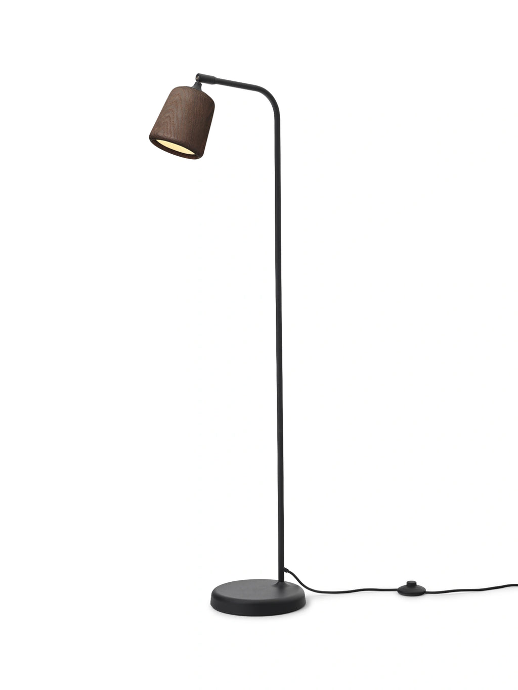 New Works Material Floor Lamp, a modern minimalist floor lamp featuring a sleek matte black metal stand with a gently curved arm and a dark walnut wood shade. The conical shade showcases a rich, visible wood grain texture, providing warm, directed light from its round base. Ideal as a contemporary reading lamp or stylish accent lighting for Scandinavian living rooms, bedrooms, or home offices.