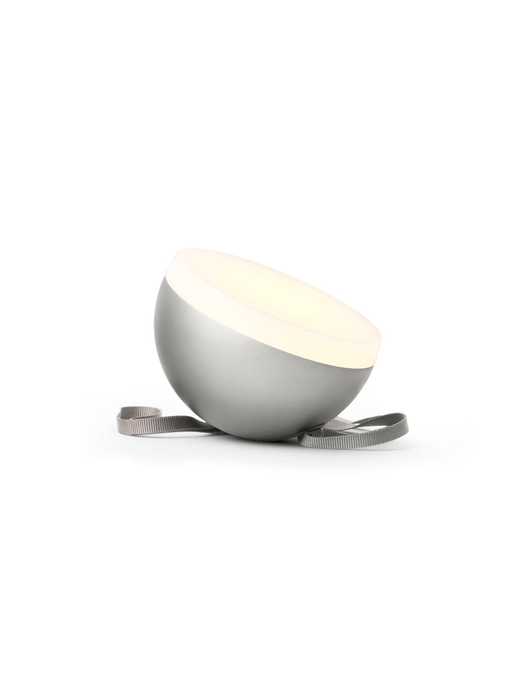 New Works Sphere Adventure Light, a sleek silver matte portable lamp with a glowing warm white top and a grey textile strap, displayed on white. Perfect for ambient lighting.