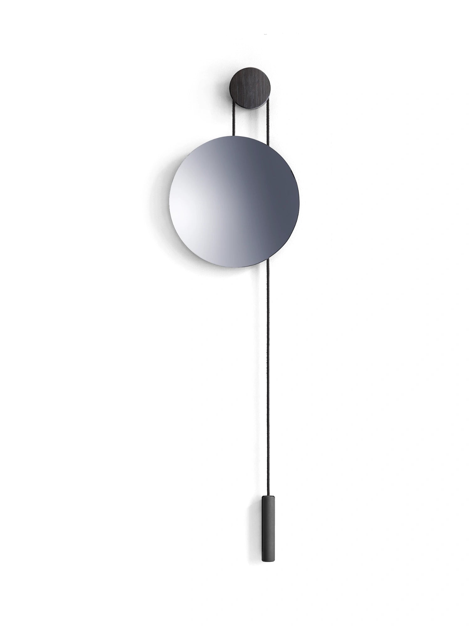 New Works Rise & Shine Wall Mirror; a round, polished silver mirror hanging from a dark wood pulley with a black cord and cylindrical counterweight against a white background. This premium, minimalist mirror is perfect for modern interiors.
