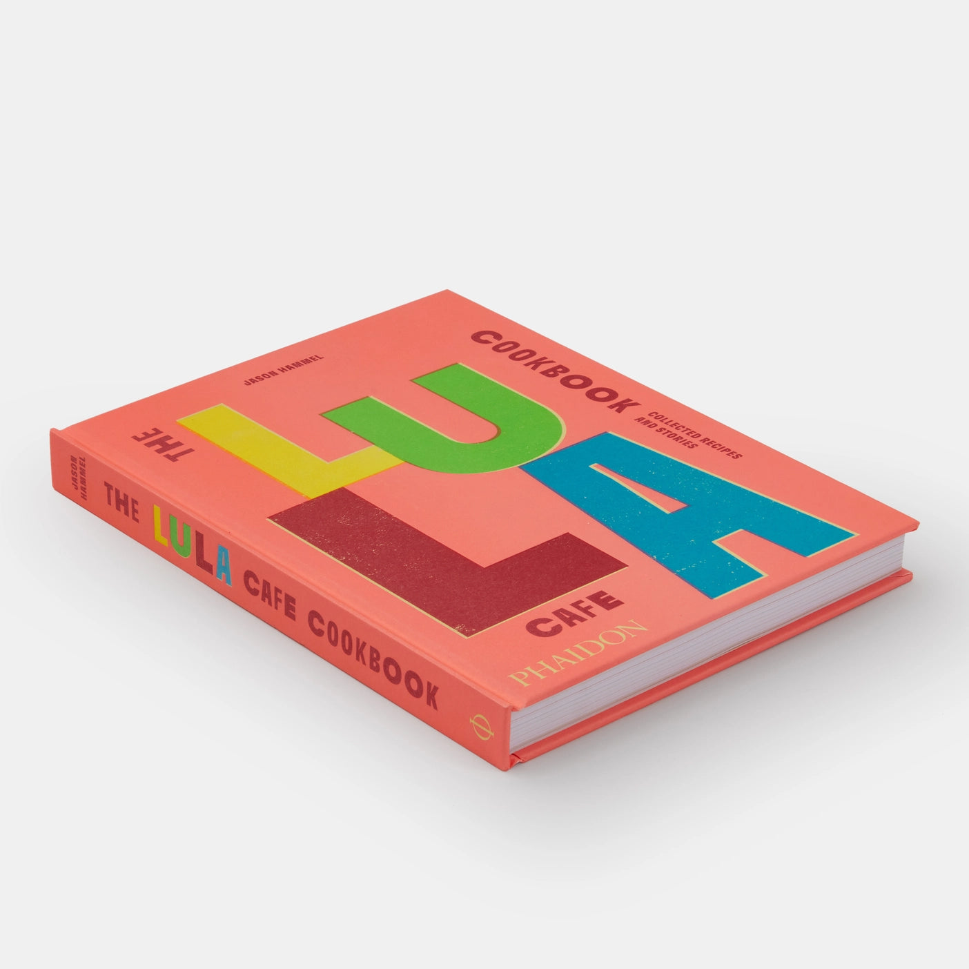  A stack of The Lula Cafe Cookbook surrounded by fresh ingredients and kitchen utensils