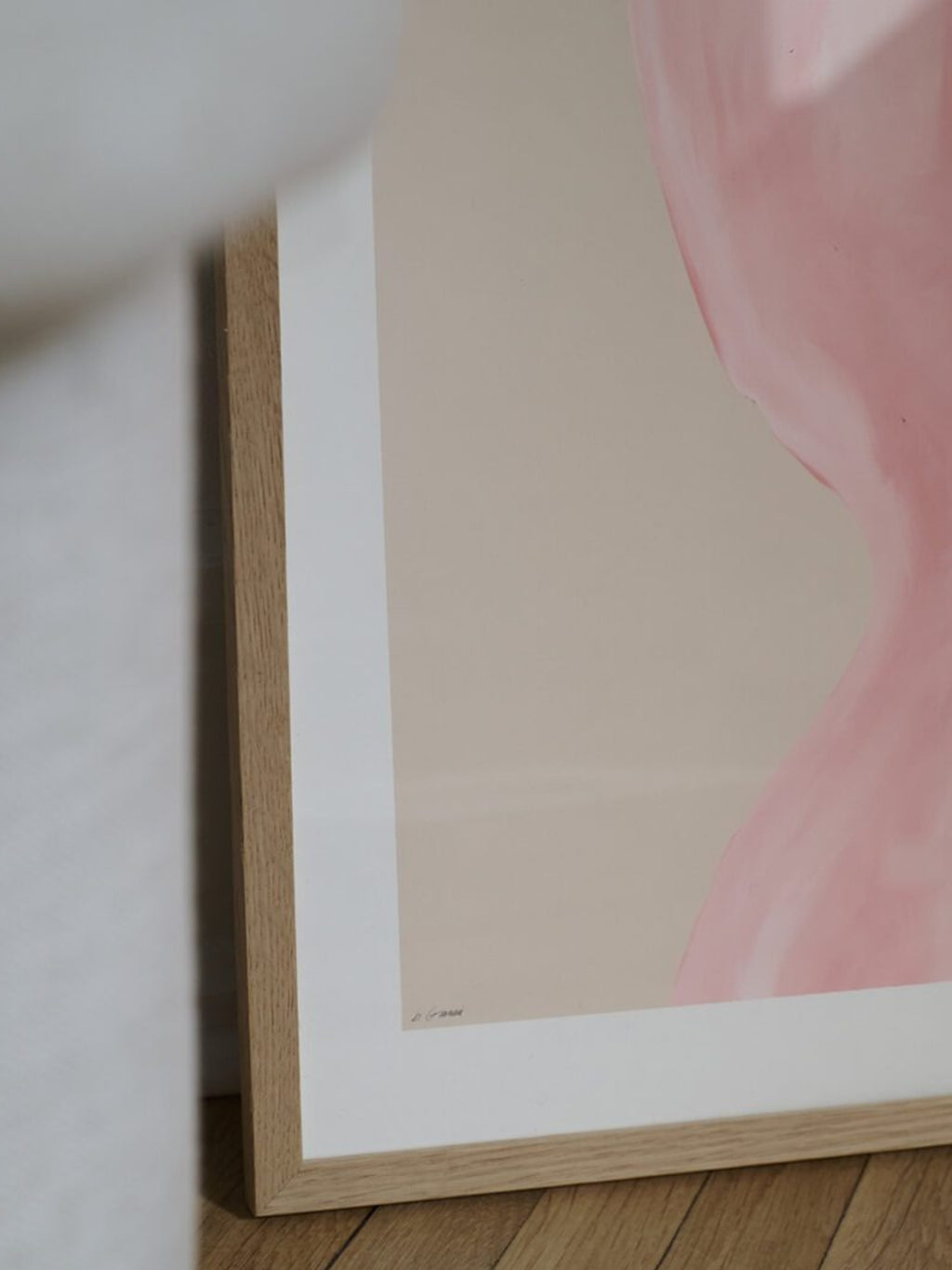 The Poster Club Abstraction, a minimalist abstract art print featuring a soft blush pink organic shape against a warm beige background, framed in light natural oak with a crisp white mat. Perfect for creating a serene contemporary gallery wall or adding a subtle pop of color to Scandinavian or organic modern living rooms and bedrooms.