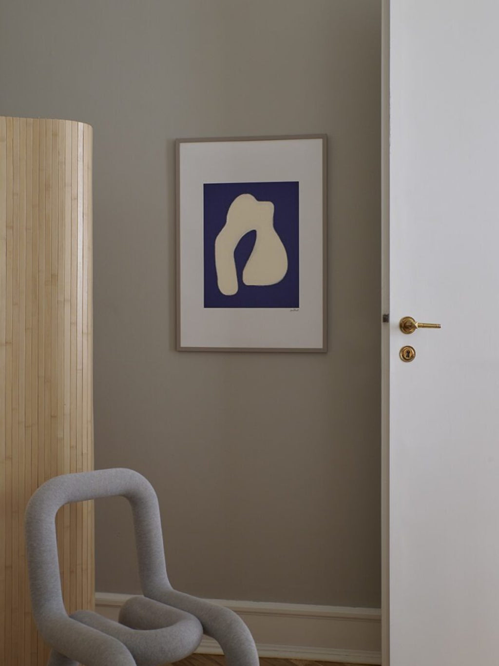 The Poster Club Shape Study 02, a minimalist abstract art print featuring a soft cream organic shape against a deep indigo blue background, presented in a light natural oak frame with a crisp white mat. This contemporary wall art piece offers a serene yet striking visual, perfect for adding an organic modern touch to Scandinavian living rooms, Japandi bedrooms, or a curated gallery wall.