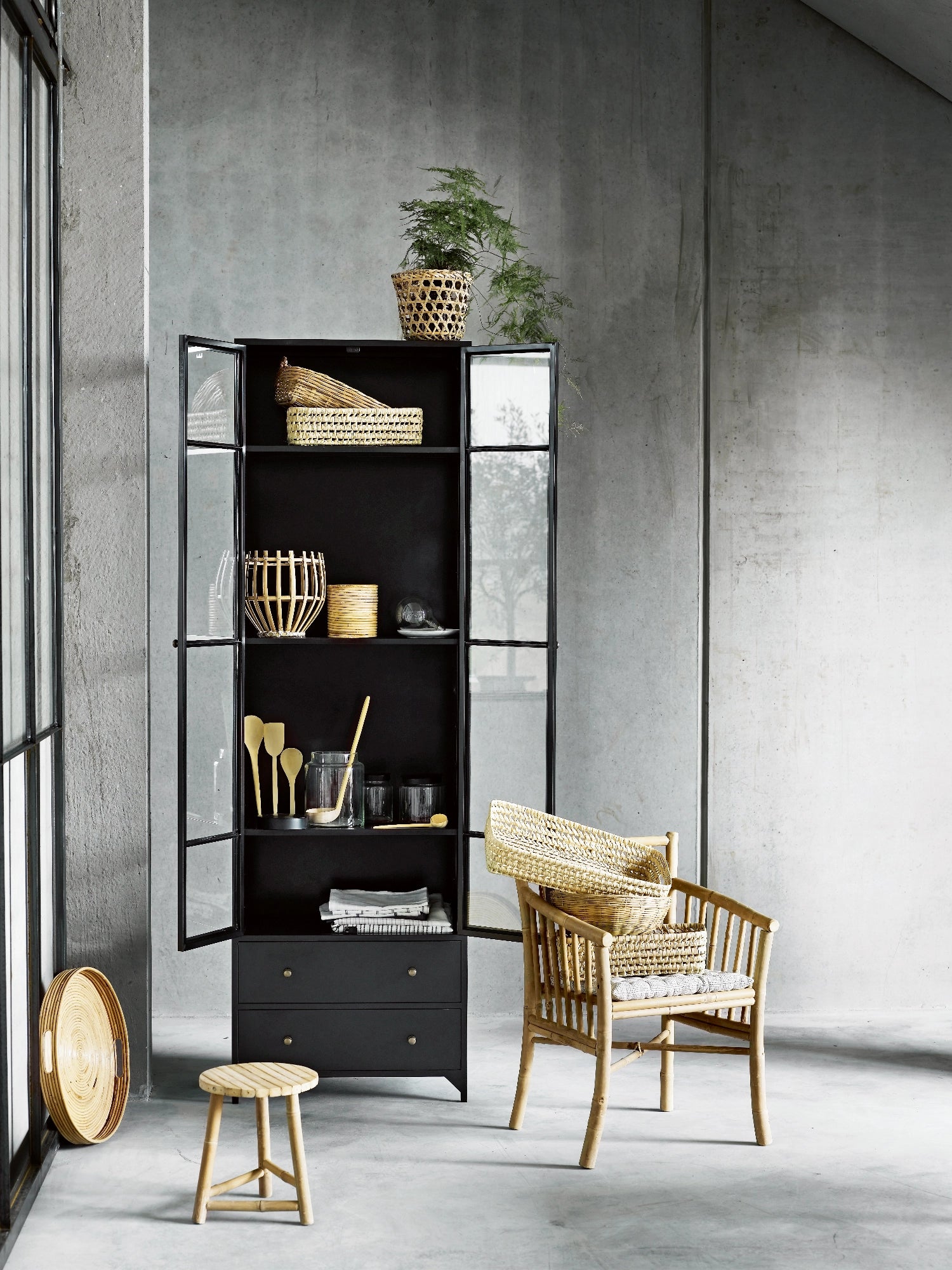 Tine K Metal High Cabinet, a tall industrial chic display cabinet crafted from matte black metal with clear glass paneled doors and two lower solid drawers featuring brass knob handles. Its clean lines and minimalist design offer versatile storage and display, blending modern aesthetics with functional organization. Perfect as a contemporary living room cabinet, kitchen pantry, or dining room display unit for industrial or modern interiors.