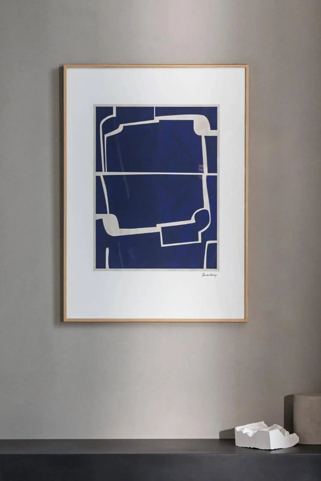 The Poster Club Faze, a modern abstract art print featuring bold organic geometric shapes in contrasting deep royal blue and off-white lines. It is presented with a crisp white mat and a sleek natural oak frame. Perfect as minimalist wall art for contemporary living rooms, bedrooms, or gallery walls.