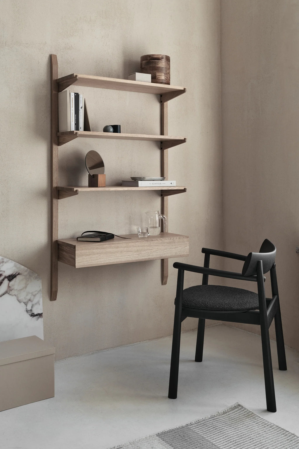 TAMO Elipsa Chair, a premium black stained wooden chair with a curved backrest and a textured dark gray seat cushion, displayed next to a light oak shelving unit. Ideal for a stylish home office or dining space.