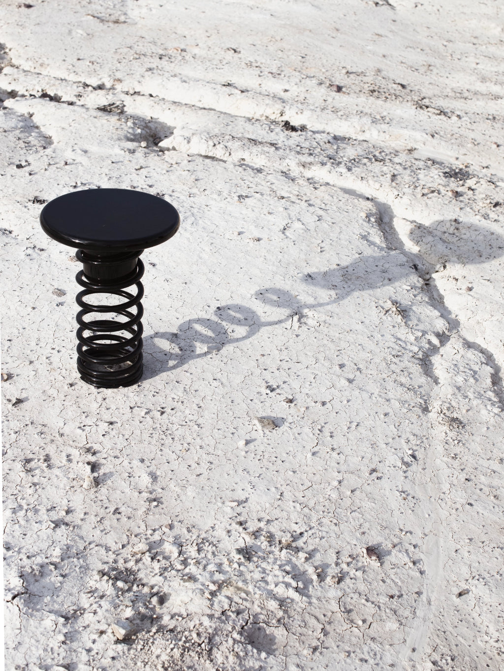 YET. Twist Stool, a striking matte black metal stool featuring a smooth, round disc top supported by a bold, industrial-style coiled spring base. Its minimalist design and sculptural form create a unique contemporary accent. Perfect as a designer stool for modern living rooms, creative workspaces, or brutalist-inspired interiors.