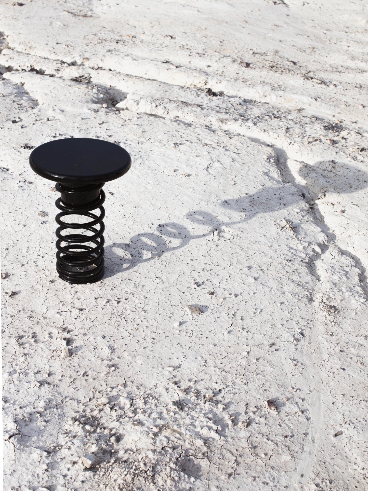 YET. Twist Stool, a striking matte black metal stool featuring a smooth, round disc top supported by a bold, industrial-style coiled spring base. Its minimalist design and sculptural form create a unique contemporary accent. Perfect as a designer stool for modern living rooms, creative workspaces, or brutalist-inspired interiors.
