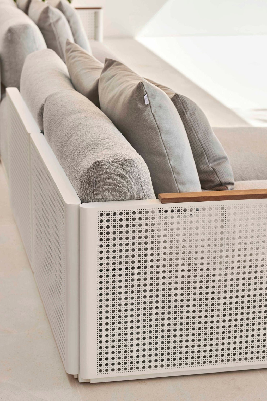 Gandia Blasco Bosc Sectional 1, a modern minimalist outdoor sofa featuring a durable white aluminum frame with distinctive perforated cane-effect side panels and a natural wood armrest accent. This contemporary outdoor sectional offers plush light grey fabric cushions and throw pillows, designed for luxurious comfort. Perfect for stylish patio lounges, terrace seating, or sophisticated outdoor living spaces.